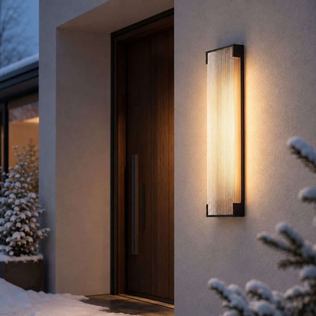 Fluted wall light beside a front door with snow-covered planting