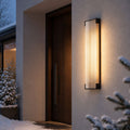 Fluted wall light beside a front door with snow-covered planting