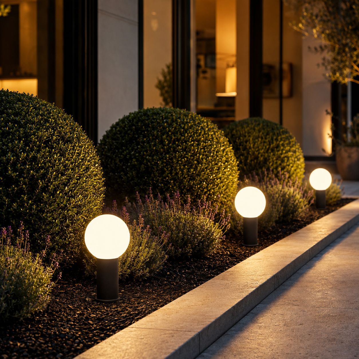 Globe bollard lights among clipped topiary and lavender beside a house