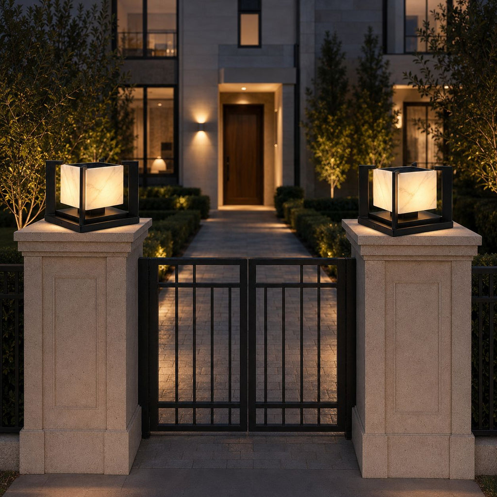 Pair of marble effect pillar lights on stone gate posts flanking iron gates