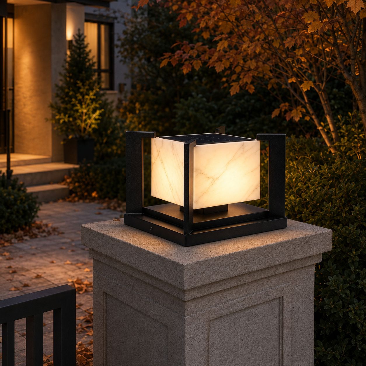 Marble effect pillar light glowing on a stone gate post beside an autumn tree