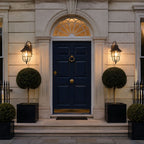 Two nautical caged sconces flanking a navy front door with box topiary