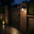 Nautical caged sconce on a brick gate pier beside a timber gate at night