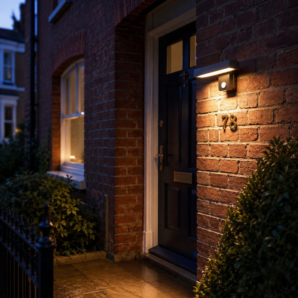 Linear LED bar wall light beside a dark front door and house number