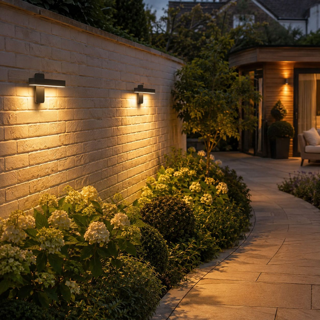 Two linear LED bar wall lights washing a pale wall above planting