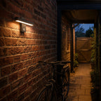 Linear LED bar wall light lighting a brick side passage with a bicycle