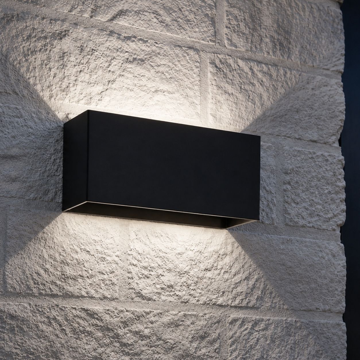 Up and down wall light on white stone throwing a soft hourglass of light