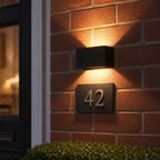 Up and down wall light above an illuminated house number forty two on brick