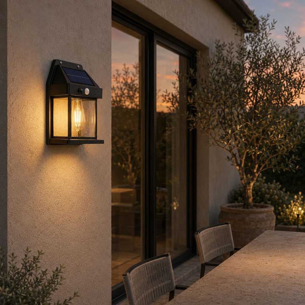 Solar wall lantern on a rendered wall beside sliding doors and an olive tree at sunset
