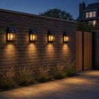 Four solar motion sensor lanterns spaced along a brick garden wall beside a timber gate