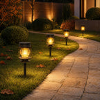 Solar lanterns on ground spikes along a lawn edge beside a stone path