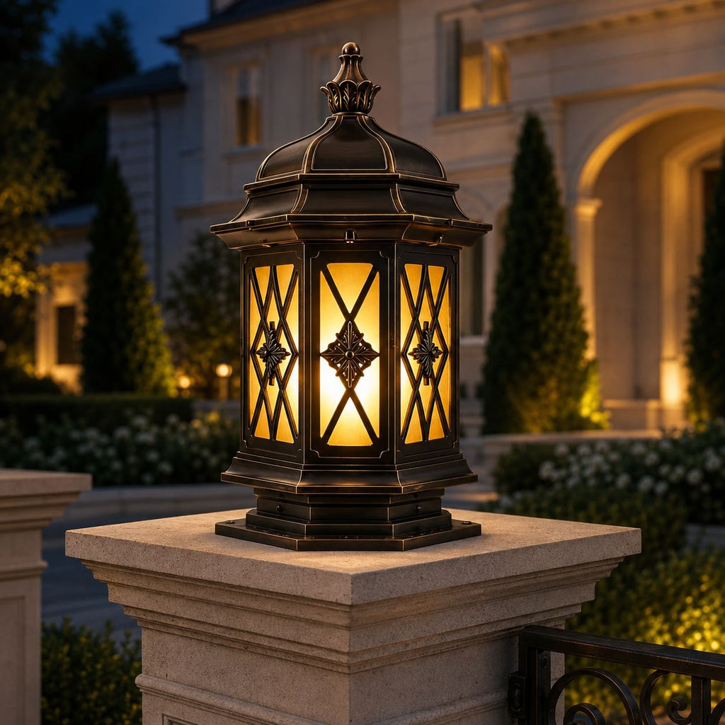 Hexagonal pillar lantern glowing on a stone pillar cap outside a cream villa