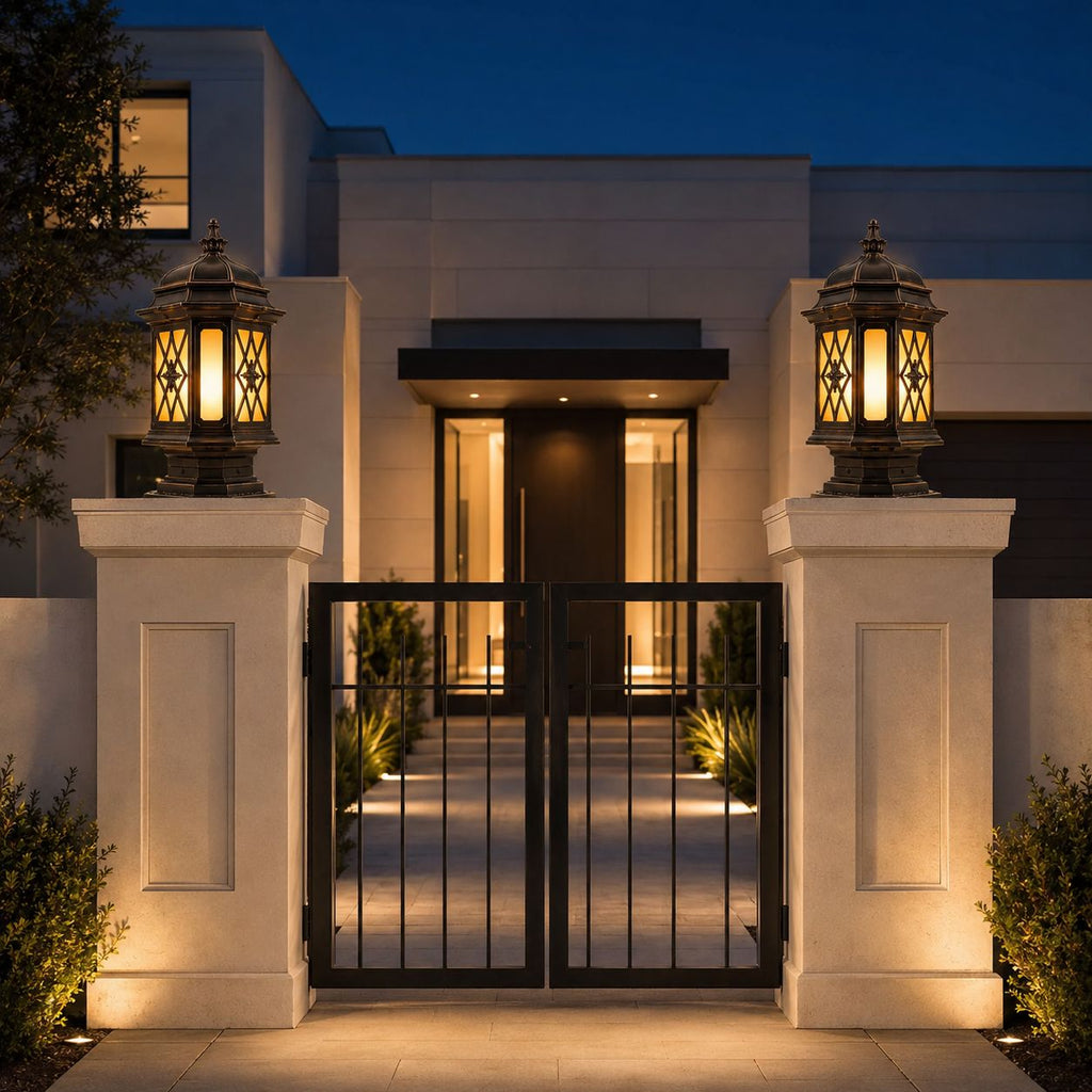 Pair of pillar lanterns on stone gate piers flanking iron gates at a modern house