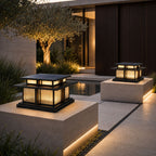 Two pier lanterns on stone piers beside an olive tree and dark timber wall