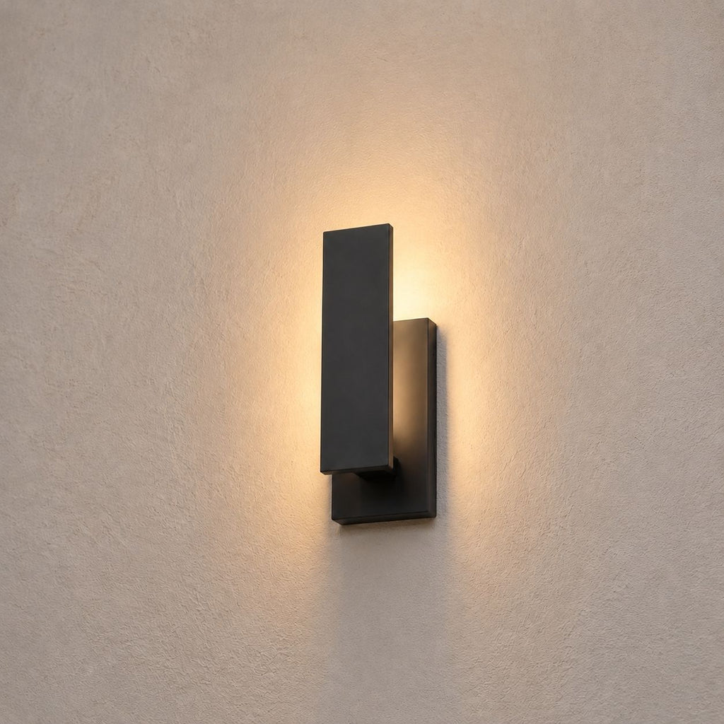 Close view of the slim black wall light washing warm light up and down a render wall