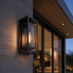 Outdoor wall sconce on a board-formed concrete wall beneath a timber soffit at dusk