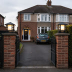 Two slatted post cap lights on brick gate piers at a driveway entrance