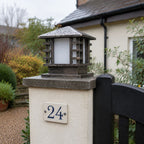 Slatted post cap light on a rendered pier beside a house number twenty four