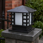 Black slatted post cap light on a stone pier beside black iron railings