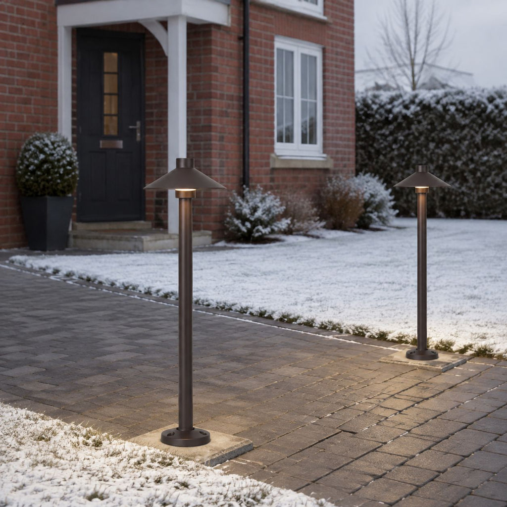 Two umbrella path lights on a snowy driveway beside a front door