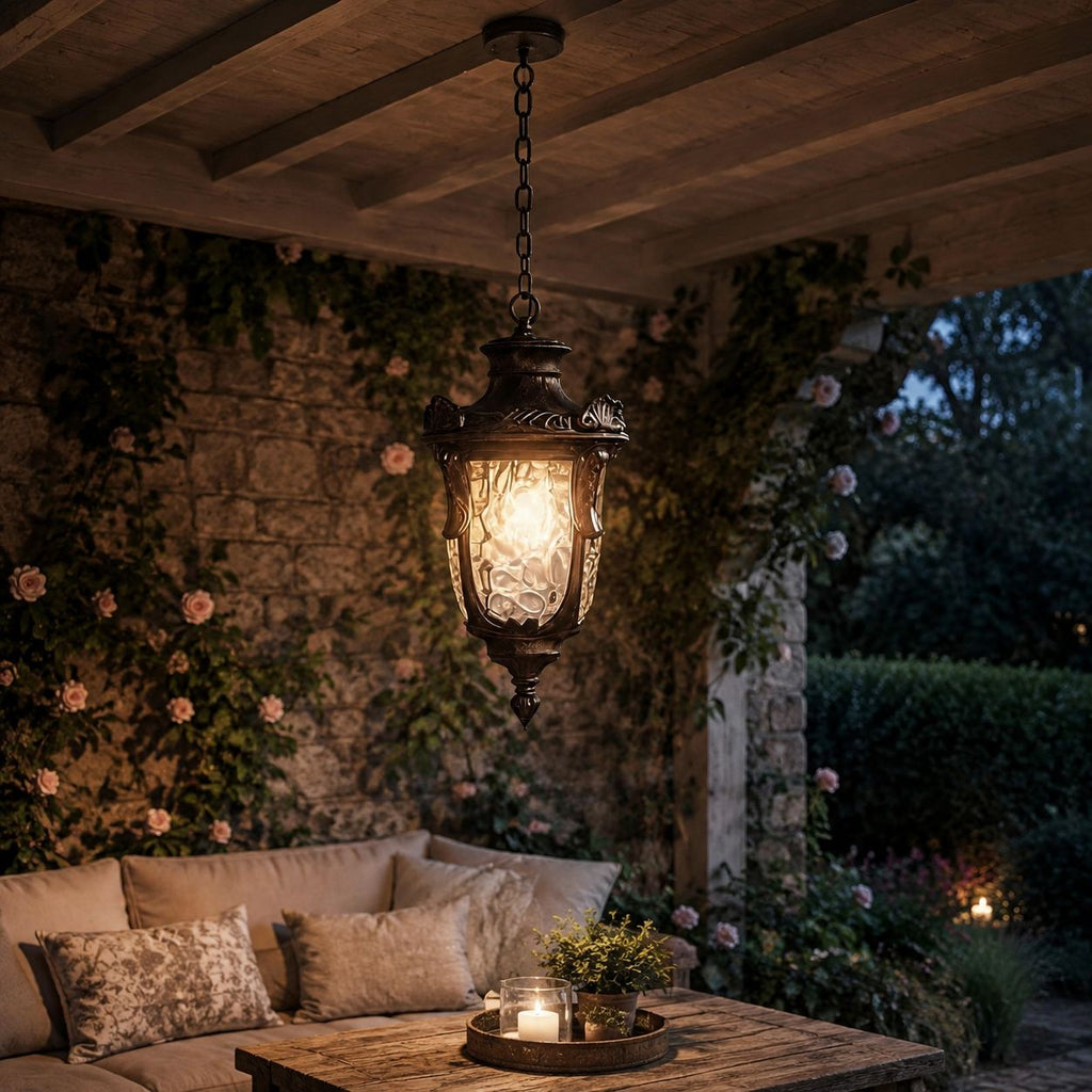 Hammered glass pendant lantern above an outdoor sofa on a rose-covered terrace