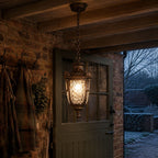 Bronze hammered glass pendant lantern hung outside a rustic brick outbuilding