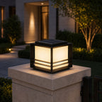 Solar pillar light glowing on a stone pillar cap beside a lit entrance
