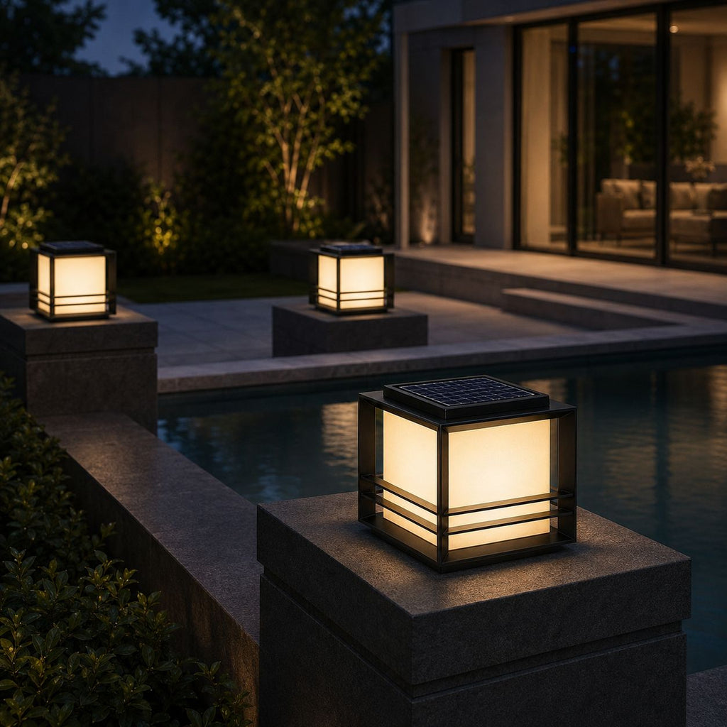 Two solar pillar lights on posts beside a modern glass-walled patio at dusk