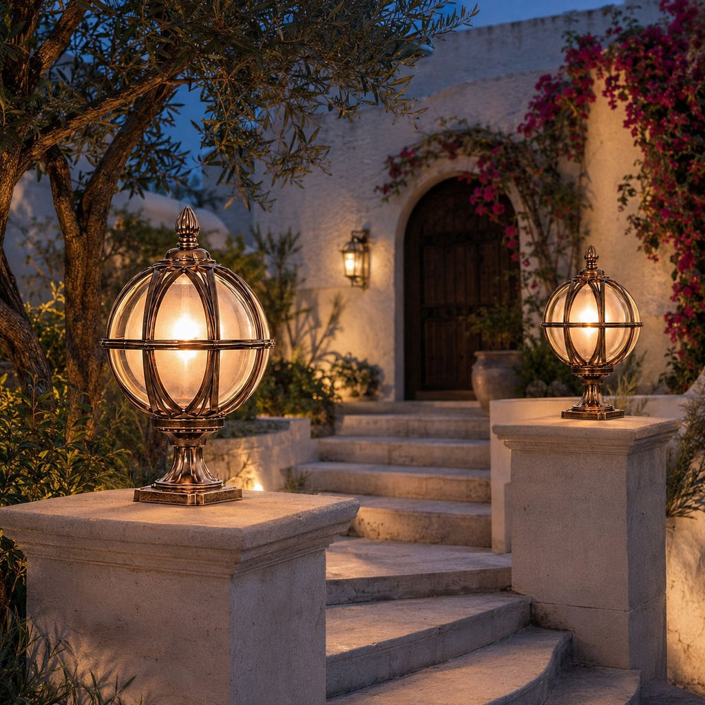 Two bronze globe post lights on stone piers beside steps to a villa with bougainvillea