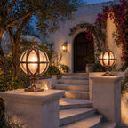 Two bronze globe post lights on stone piers beside steps to a villa with bougainvillea