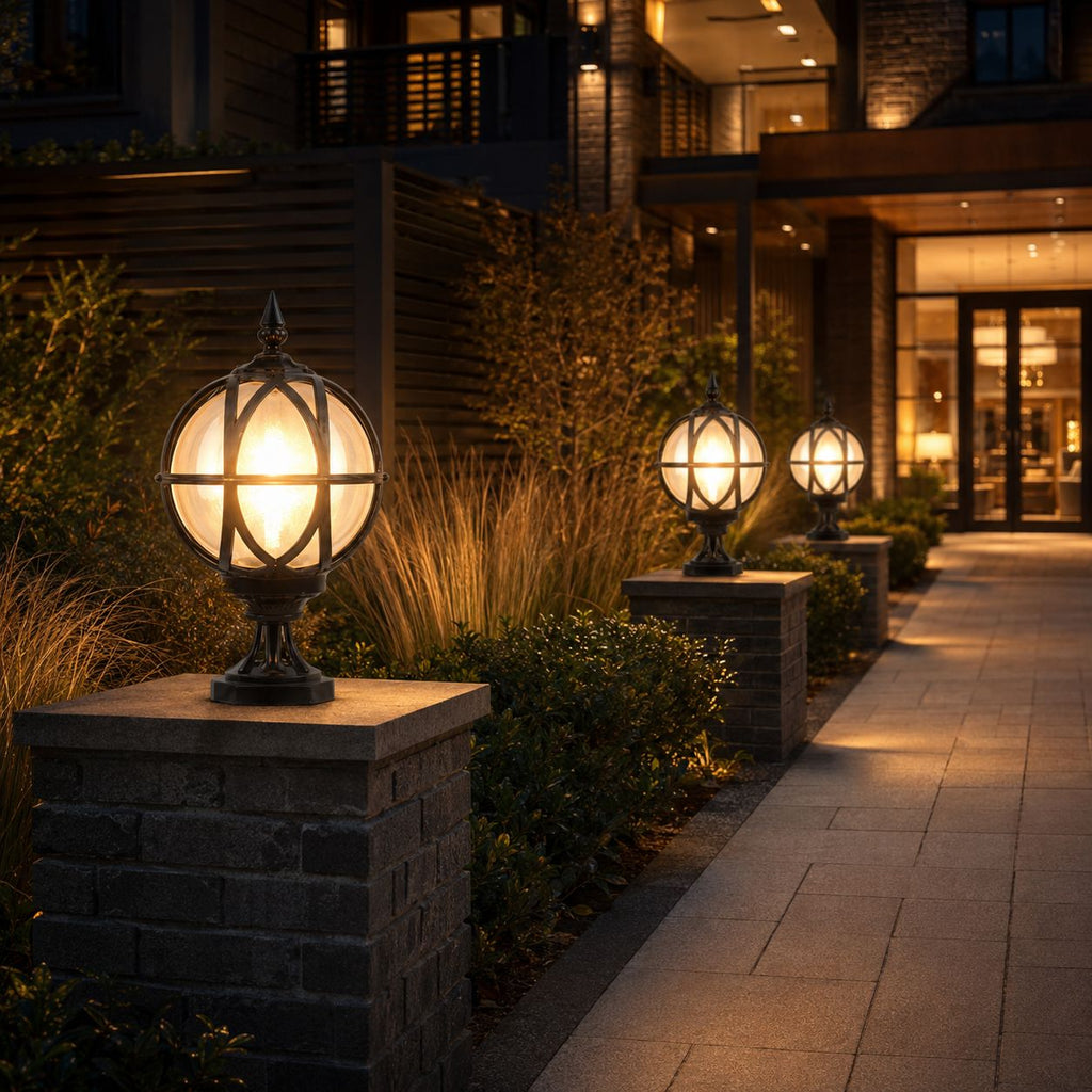 Three black globe post lights along a stone pillar walkway outside a modern building at dusk