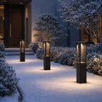 Three bollard lights lighting a snow-covered path to a dark front door