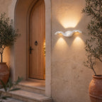 White wave wall light in warm white on render beside a timber front door