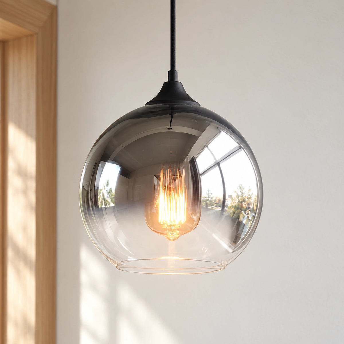 Glasstone Silver pendant illuminated, with a warm glow beneath the smoked grey upper globe