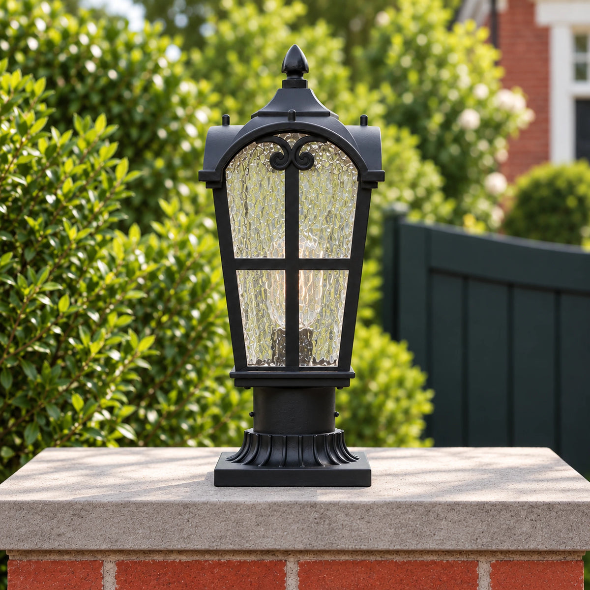 Front view of a Sentora matte black pillar lantern with textured glass and a flared base on a brick gate pier.