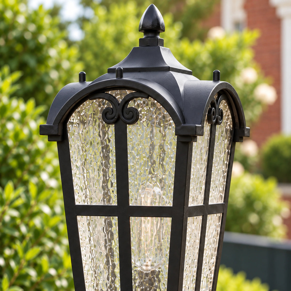 Close-up of the Sentora matte black pillar lantern's decorative roof, top finial and textured-glass panels.