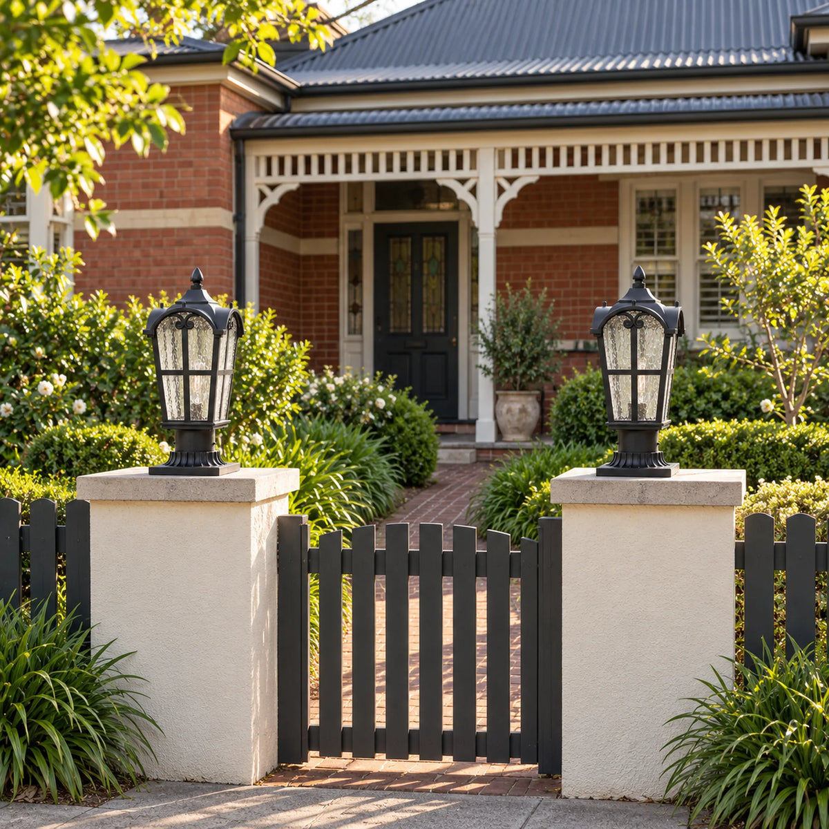 Two Sentora matte black pillar lanterns on rendered gate pillars outside a brick home; installation example.