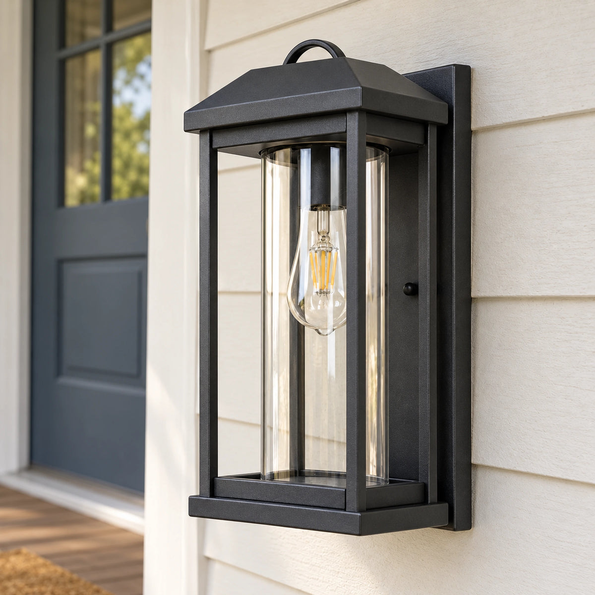 Angled daylight view of the CharcoalGlow black wall lantern, showing the frame depth and clear cylindrical glass.