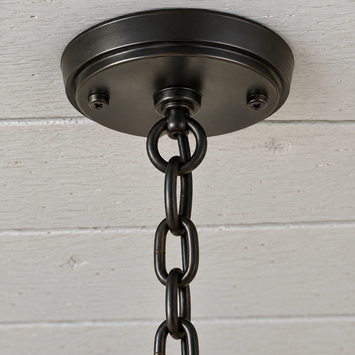 Close-up of the Portiva round black ceiling canopy, hanging ring and interlocking suspension-chain links.