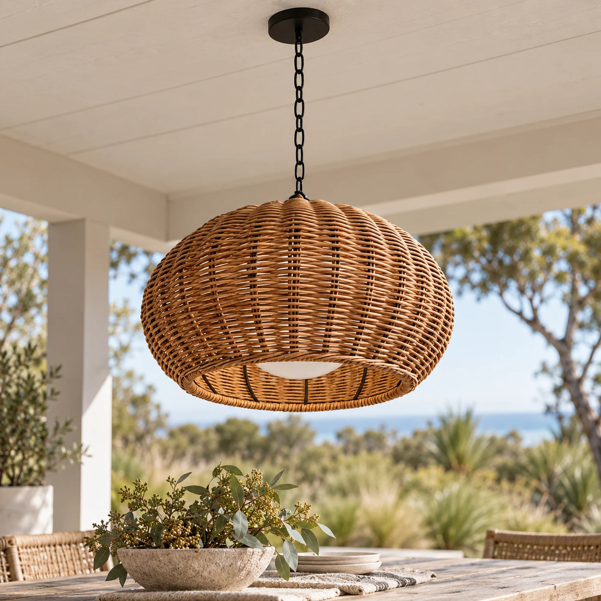 Large woven Weavora pendant hanging above an outdoor dining table beneath a white coastal verandah ceiling.