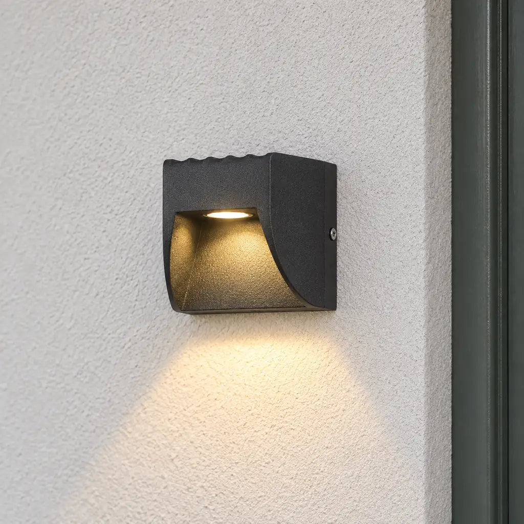 Luminara 9cm black outdoor downlight on a pale rendered wall beside a sage door frame